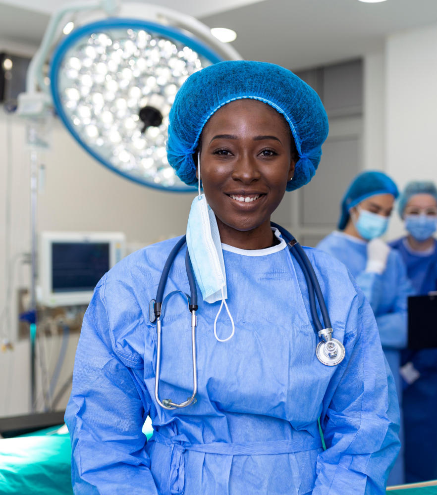 Portrait of happy African woman surgeon standing in operating room